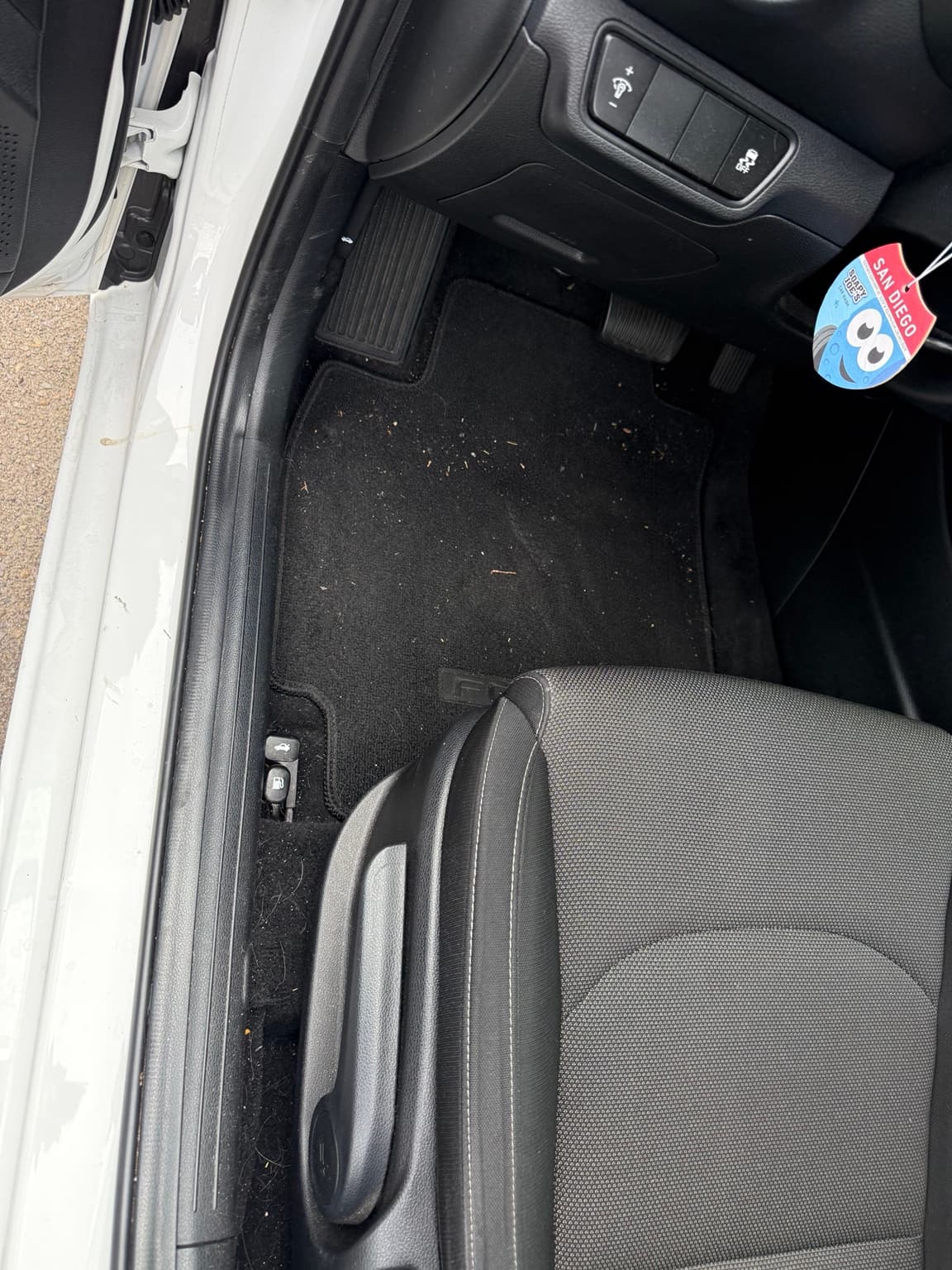 Crumbs and debris on the white Kia driver floor mat before an Express Detail