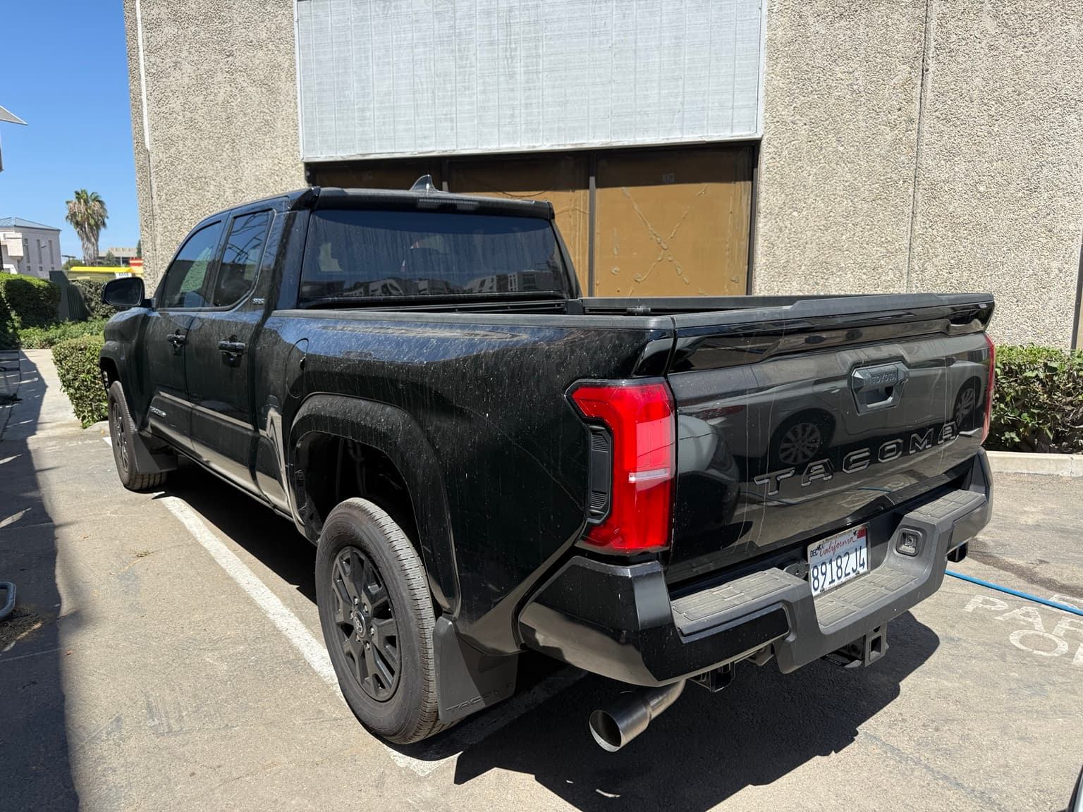 Dust and dirt on the rear and side of a black Toyota Tacoma before an Exterior Detail