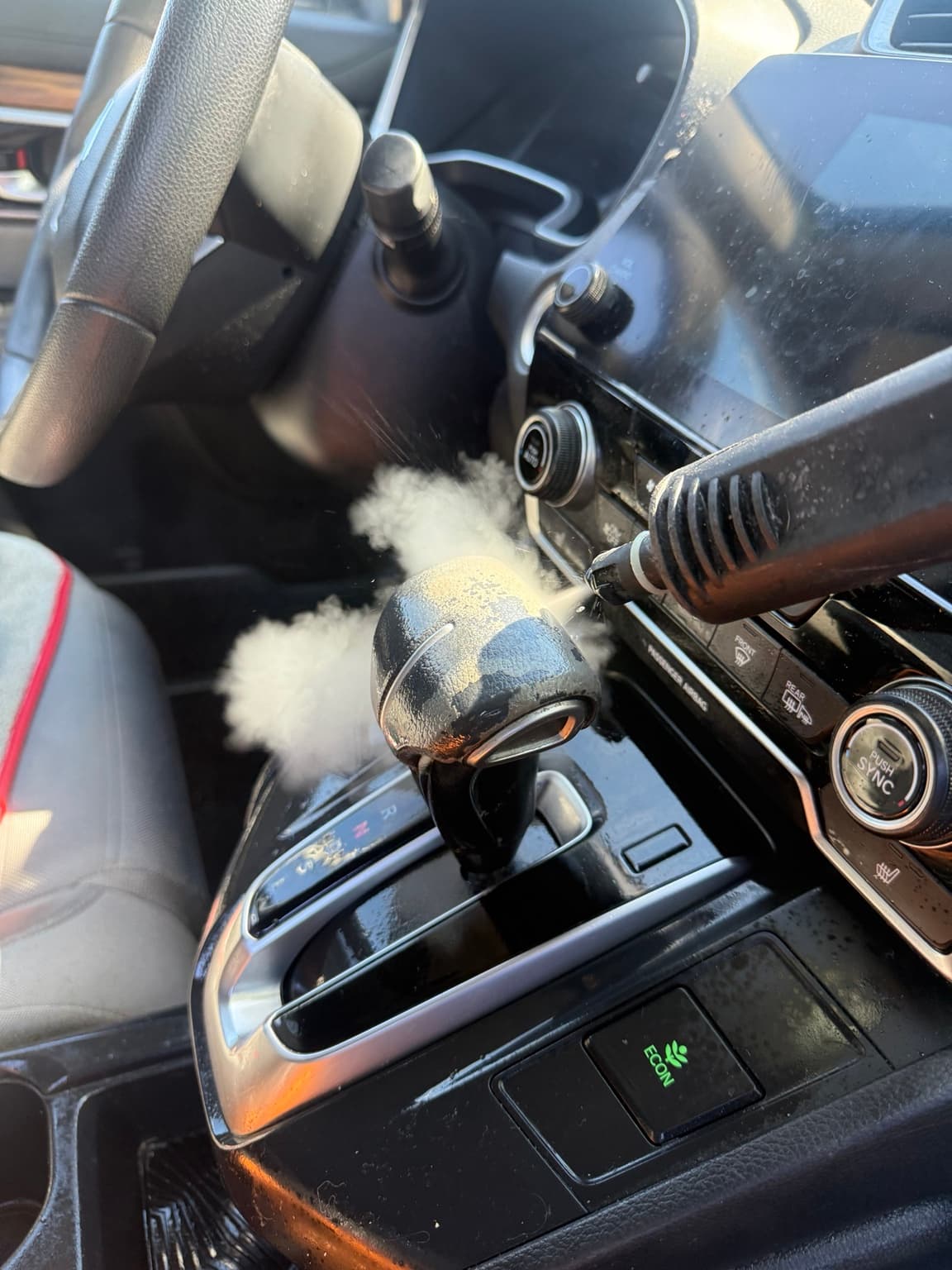 Steam cleaner working around an interior gear selector and center console
